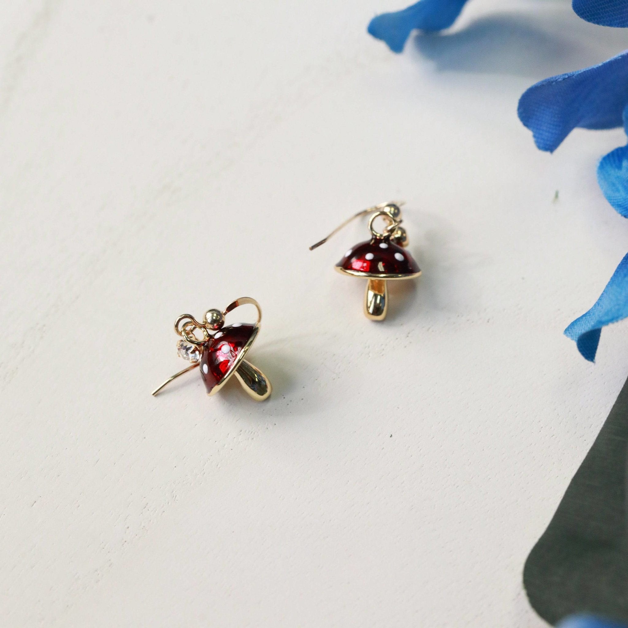 tiny mushroom charm earrings in red with white dots on 14kt gold filled earring hooks with tiny crystal charms front view